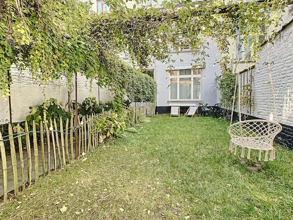 Un jardin à l'arrière d'une maison à Bruxelles avec balançoire