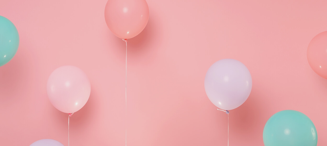 des ballons gonflés et multicolores sur fond rose pour une fête d'enfant